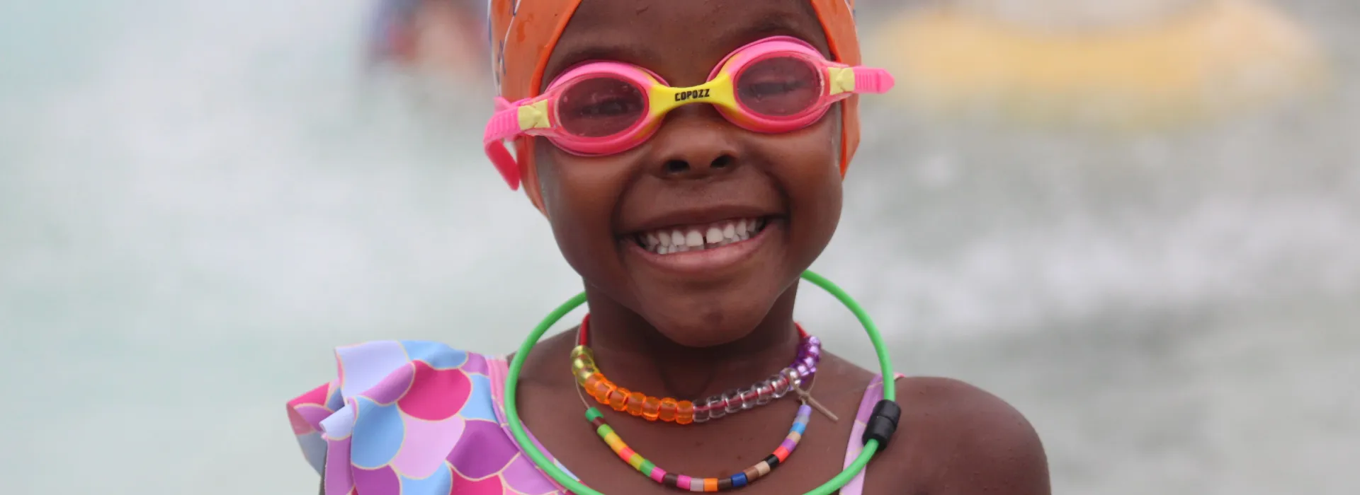 Cute girl black girl in pink goggles and orange swim cap