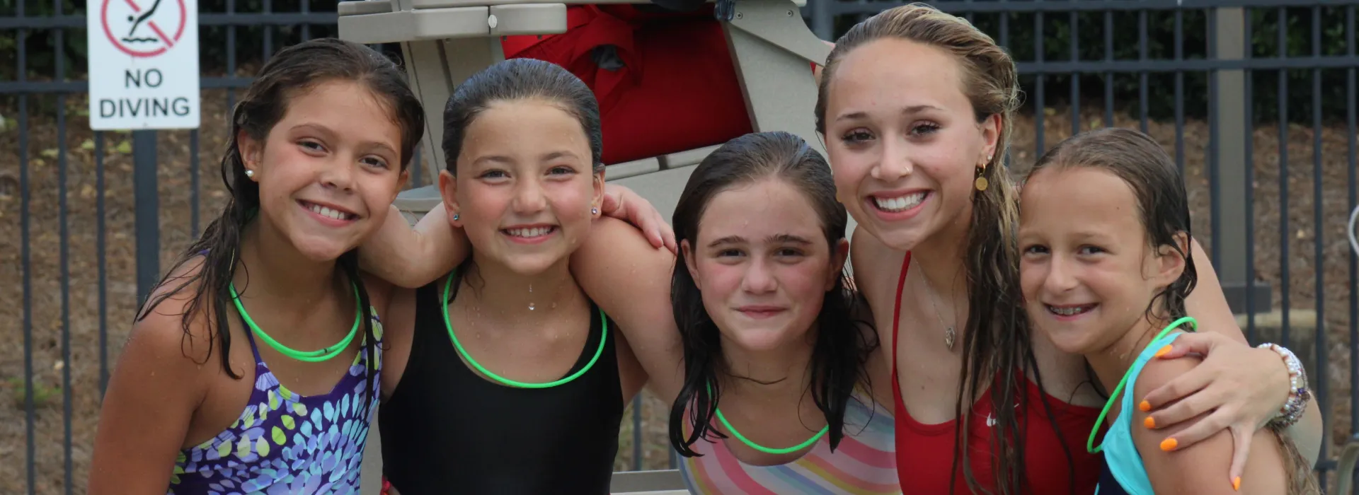 5 girls standing wet by the pool